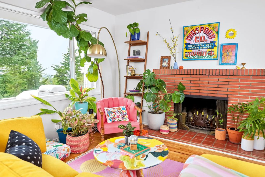 Vibrant living room with colorful furniture, plants, and brick fireplace.
