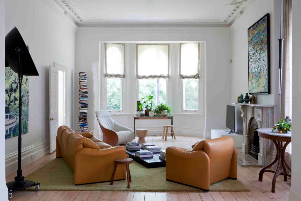 Bright living room with tan leather sofas, large windows, and modern decor.