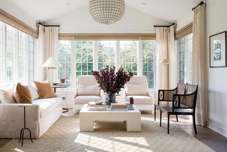 Elegant living room with white furniture, natural light, and soft tones.